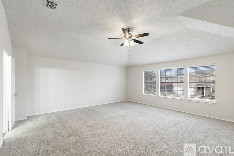A spacious room with a ceiling fan and carpeted floor.