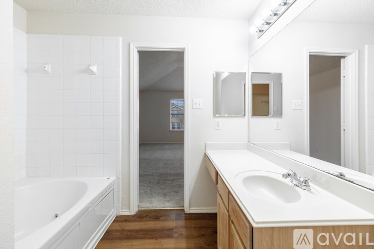 A bathroom with a tub, sink, and mirror.