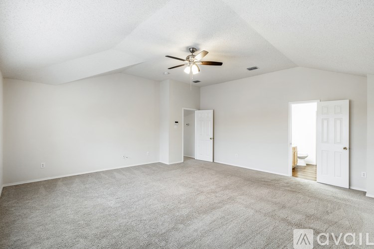 A spacious room with a ceiling fan and carpeted floor.