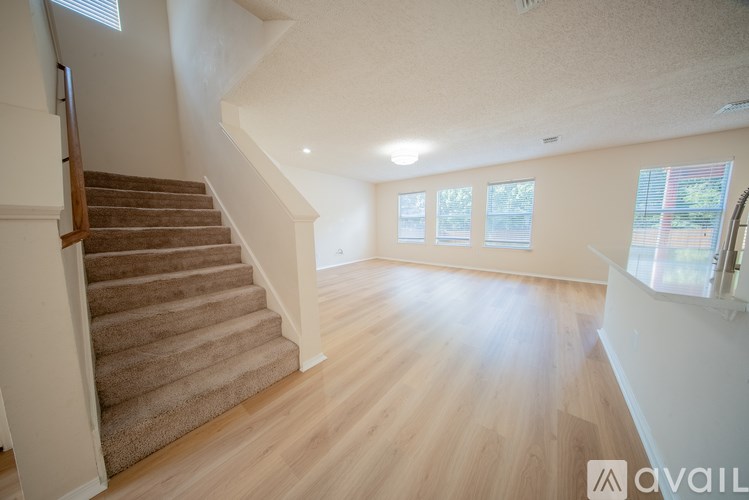 A spacious room with wooden floors and a staircase leading to another level.