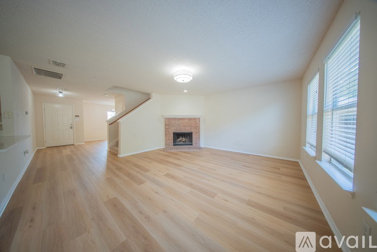 A spacious room with wooden floors and a fireplace.