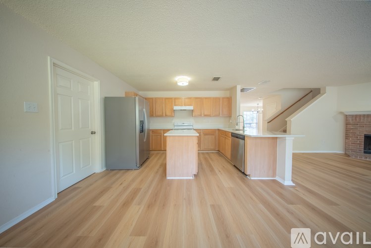 A spacious kitchen with wooden floors and a refrigerator.