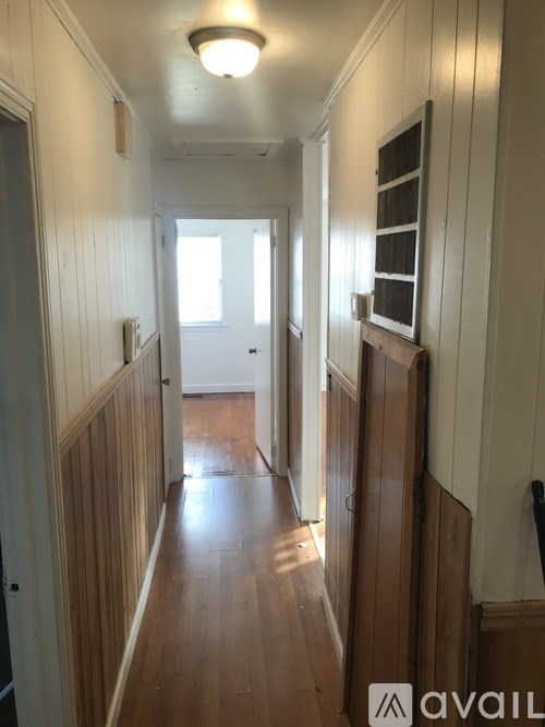 A long hallway with wooden floors and white walls.