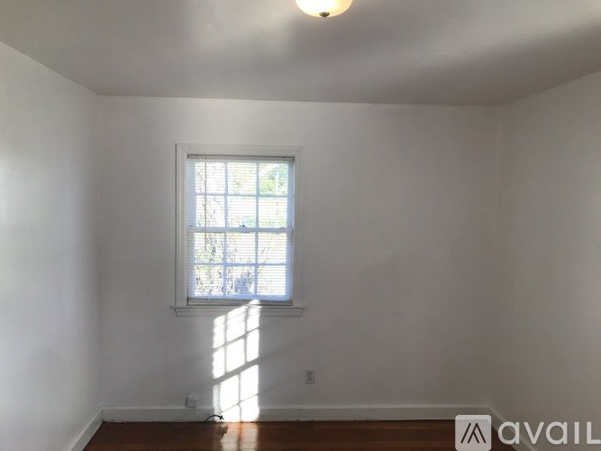 A room with a window and a wooden floor.
