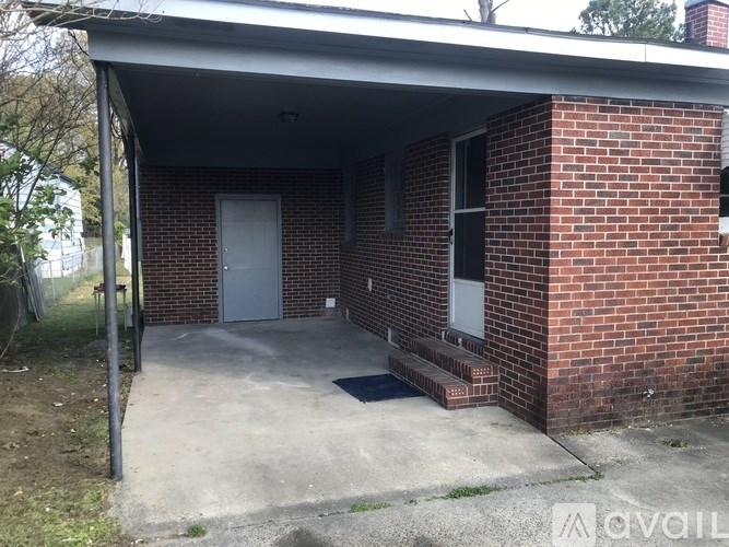 A red brick house with a white door and a grey garage door.
