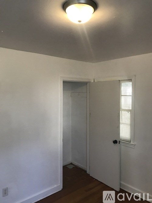 A white hallway with a door and a light on the ceiling.