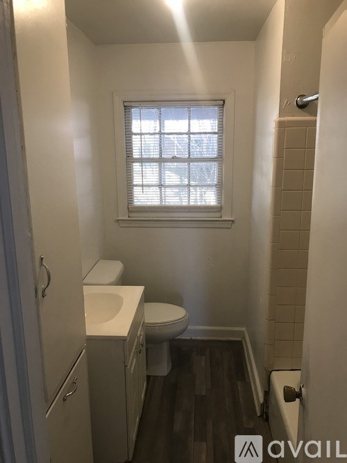 A small bathroom with a toilet, sink, and a window.