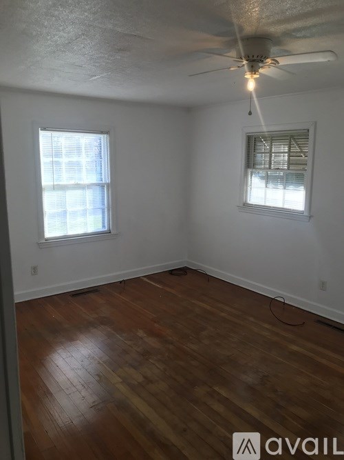 A room with wooden floors and two windows.