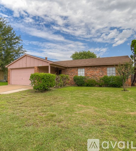 A house with a brown roof and a brown garage door is surrounded by a green lawn.