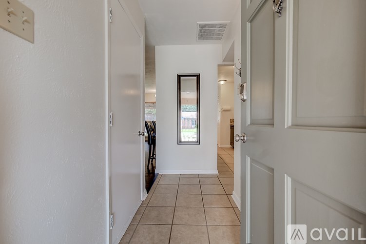 A hallway with a door on the right and a window in the middle of the room.