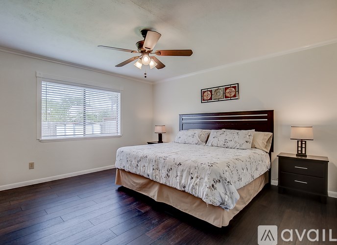 A bedroom with a bed, two lamps, and a ceiling fan.