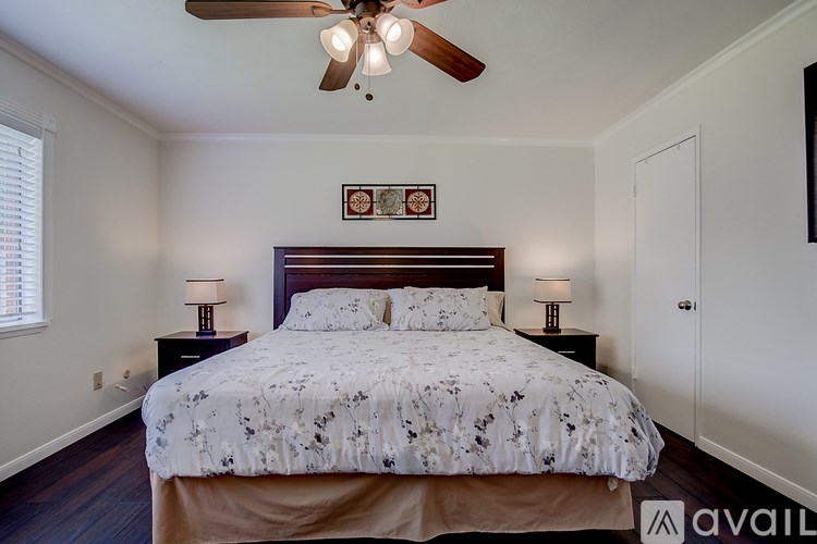 A bedroom with a bed, two lamps, and a ceiling fan.