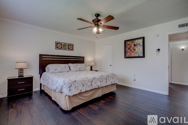 A bedroom with a bed, two lamps, a ceiling fan, and two pictures on the wall.