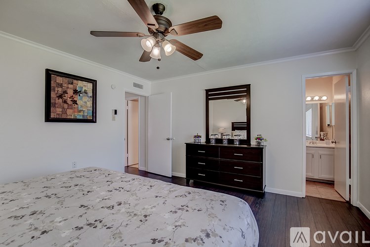A bedroom with a floral patterned bedspread and a ceiling fan.