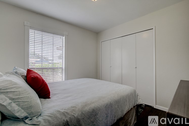 A bedroom with a bed, a window with blinds, and a wardrobe.
