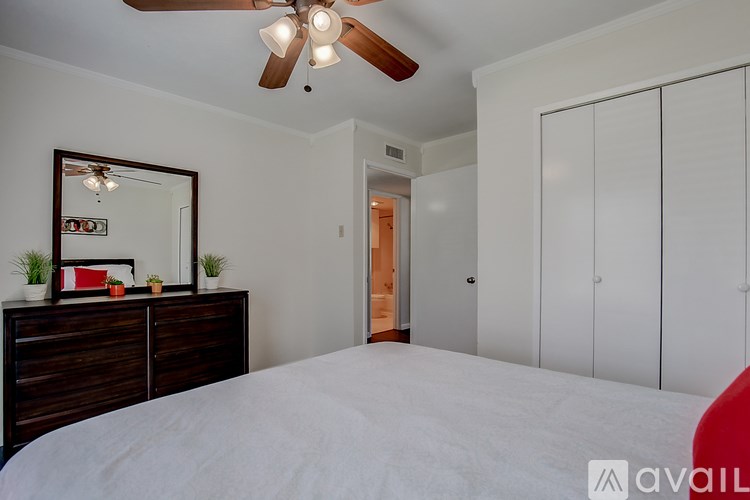 A bedroom with a bed, dresser, mirror, and a ceiling fan.