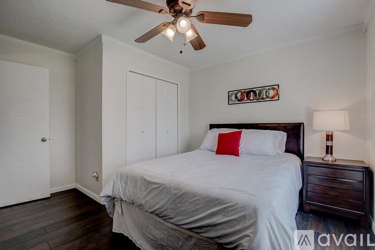 A bedroom with a bed, nightstand, and a ceiling fan.