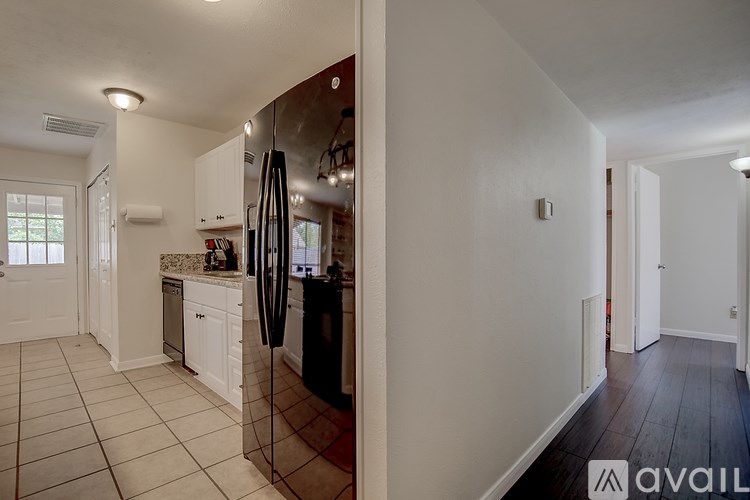 A kitchen with white cabinets and a black refrigerator.