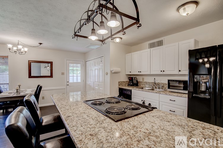A kitchen with granite countertops and a black stove top.