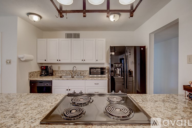 A kitchen with a stove top in the middle of a tiled floor.