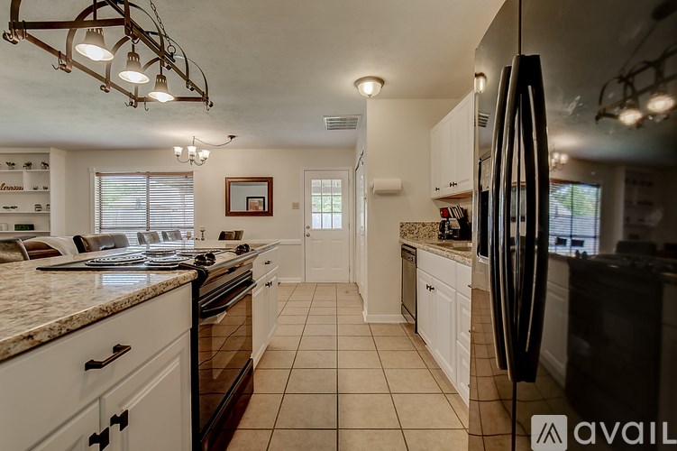 A kitchen with white cabinets and a black refrigerator.