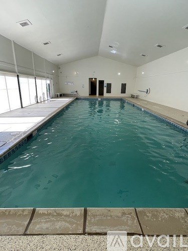 A large indoor swimming pool with a tiled edge and a diving board.