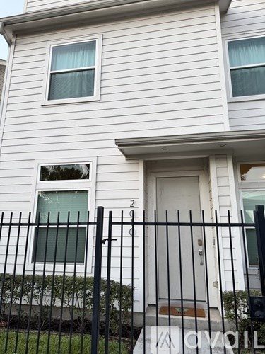 A white house with a black fence in front.