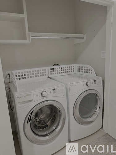 Two white front load washing machines in a small laundry room.