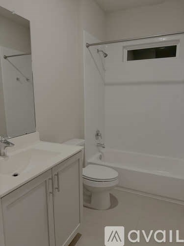 A white bathroom with a toilet, sink, and mirror.