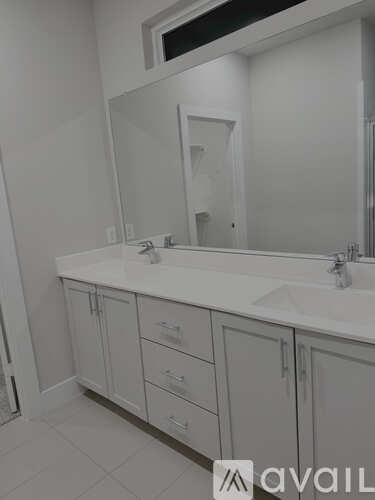 A bathroom with a white sink and cabinets.