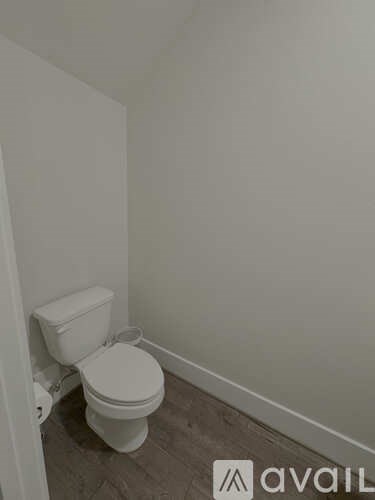 A white toilet in a small room with a wooden floor.