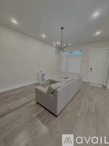 A living room with a white couch and a chandelier.