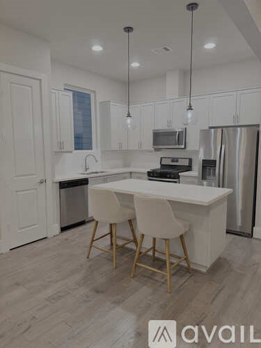 A kitchen with a white island and two chairs.