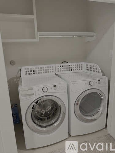 Two white front load washing machines in a small laundry room.