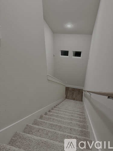 A staircase with a carpeted runner and white walls.