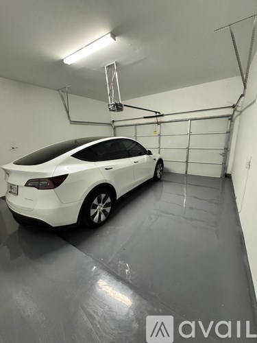 A white car is parked in a garage with a grey floor.