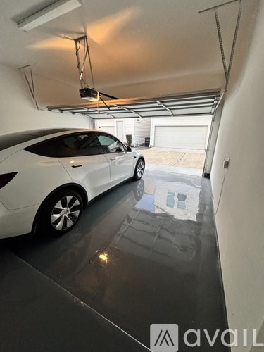 A white car is parked in a garage with a logo that reads "avaiL" on the wall.