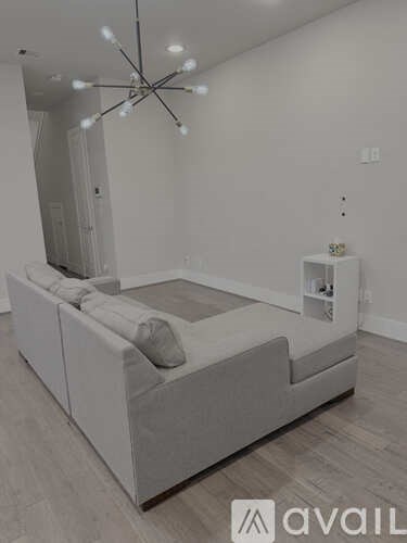 A modern living room with a large sectional sofa and a chandelier.