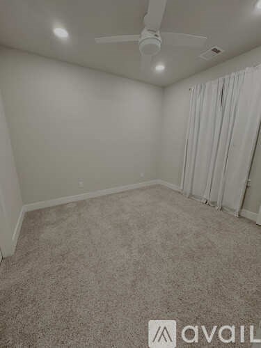 A room with a carpeted floor and a ceiling fan.