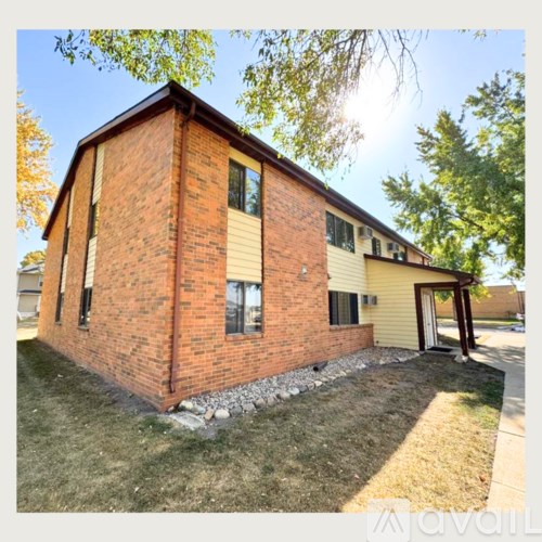 A red brick house with a yellow siding and a white door.