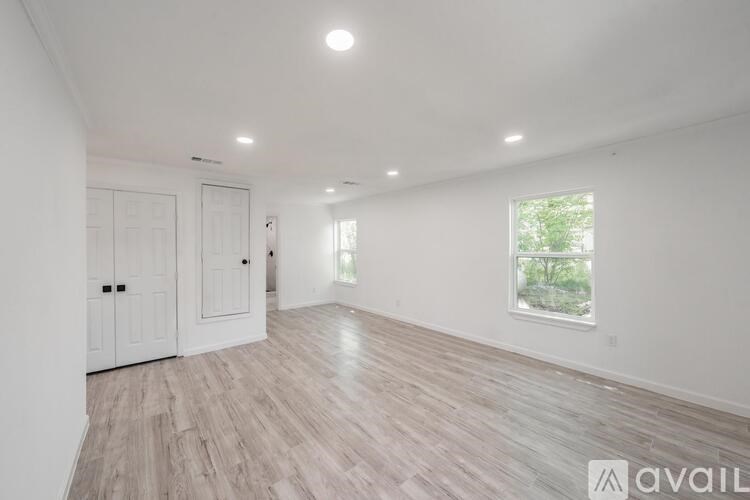 A spacious room with wooden flooring and white walls.
