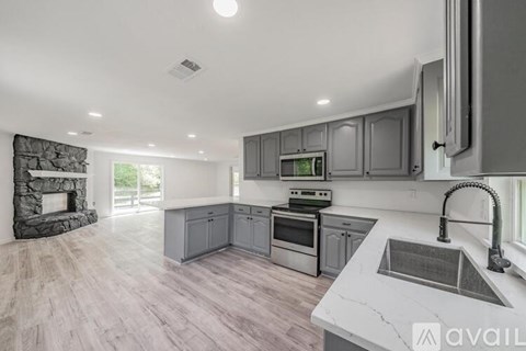 A modern kitchen with a stone fireplace and a marble countertop.
