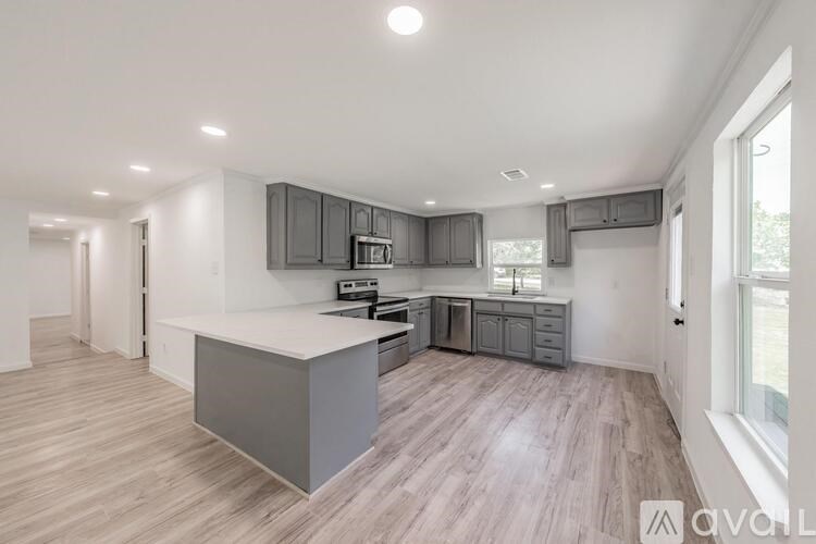 A modern kitchen with wooden floors and grey cabinets.