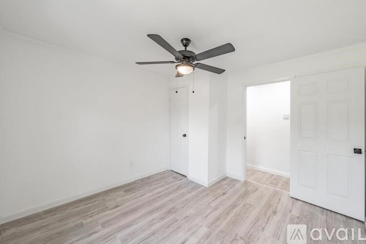 A room with a ceiling fan and wooden flooring.