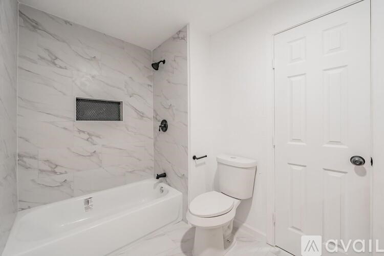 A bathroom with a marble wall and a white bathtub and toilet.
