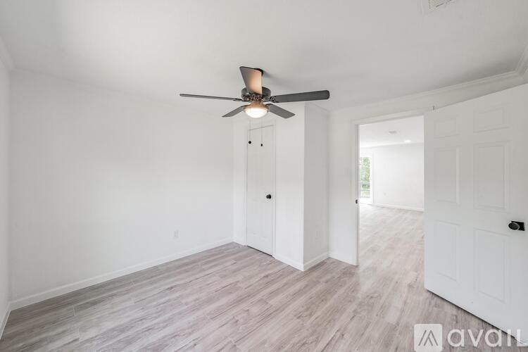 A room with a ceiling fan and light fixture, and a wooden floor.