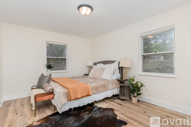 A bedroom with a bed, two lamps, and a cowhide rug.