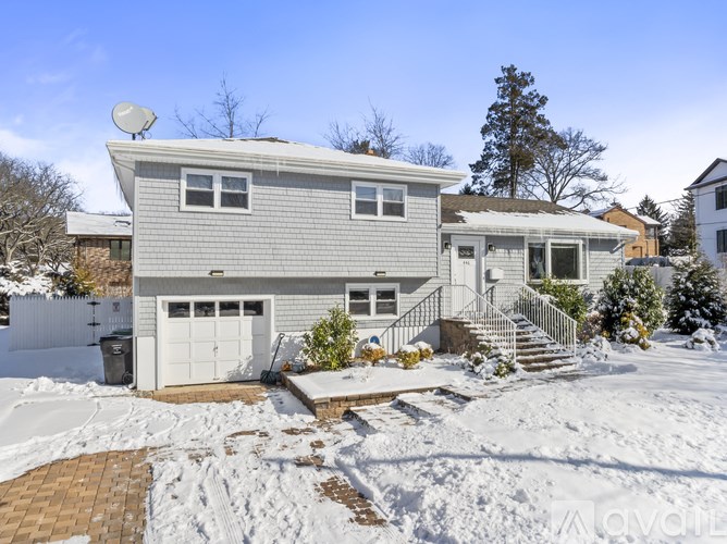A house with a grey roof and white garage door is surrounded by snow.