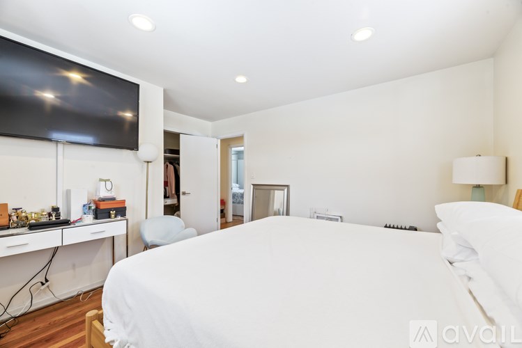 A bedroom with a large bed and a television mounted on the wall.