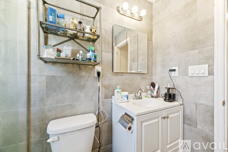 A bathroom with a toilet, sink, and shelves with toiletries.